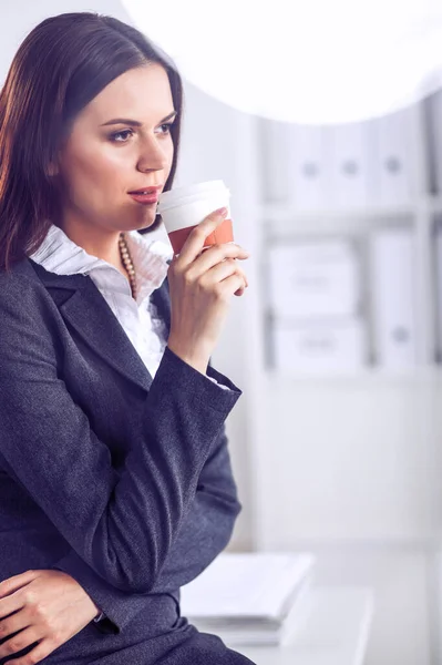 漂亮的女商人在明亮的办公室里喝咖啡 — 图库照片