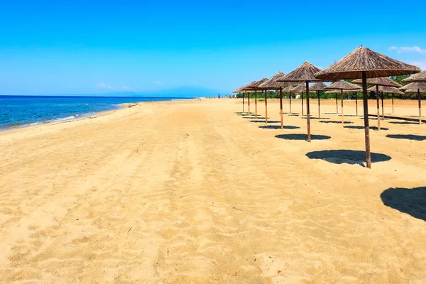 Reihe von hölzernen Sonnenschirmen am Sandstrand, Meer — Stockfoto