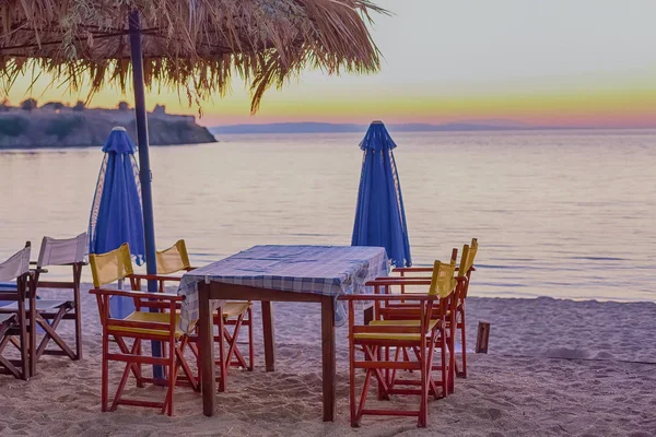 Sedie e ombrellone in spiaggia al tramonto — Foto Stock