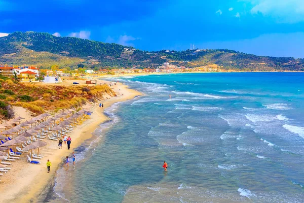 Strandhintergrund mit türkisfarbenen Meereswellen und Sonnenschirmen, Griechenland — Stockfoto