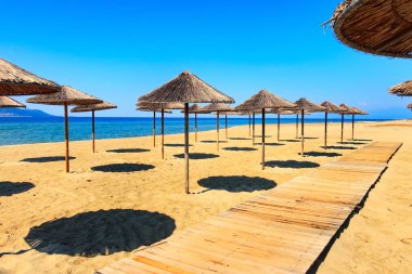 Satır kumlu plaj, deniz, ahşap şemsiye