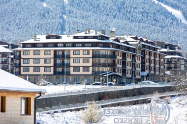 Bansko, Bulgaria - April 9, 2025: Glazne river in bulgarian town, hotel houses and snow Pirin mountains