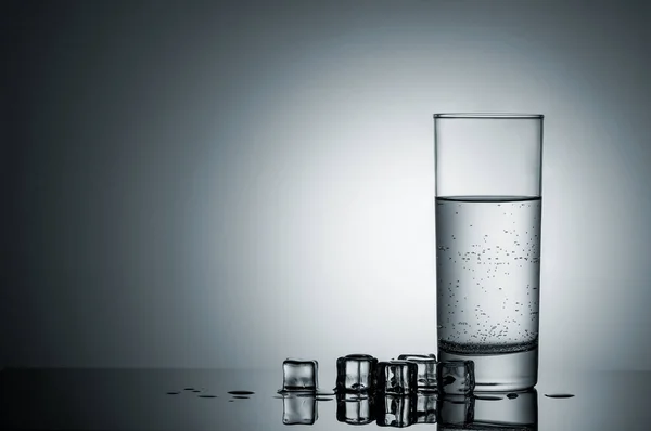 Vaso de agua y cubitos de hielo derretidos cerca — Foto de Stock