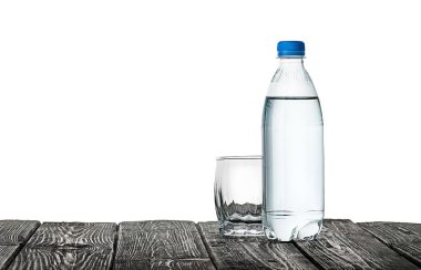 Boş bardak ve şişe suyu. Ahşap bir masa üzerinde plastik şişe. Beyaz arka plan üzerinde izole.