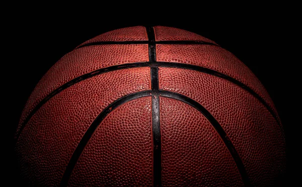 上から照らされたバスケットボールボールの一部 黒を背景に — ストック写真