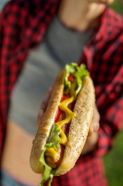 Açık havada piknik zamanı, sosisli sandviç odaklanmak sırasında park, klasik Amerikan Sosisli sandviç yeme kadın