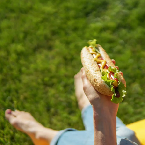 ピクニックに ホットドッグに焦点の間に屋外公園 古典的なアメリカのホットドッグを食べる女 — ストック写真