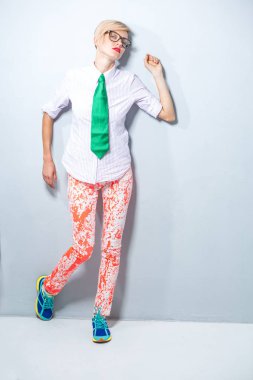 Yeşil kravat, gömlek ve parlak pantolon ışık arka plan izole trendy kıyafetler, şık sarışın kız moda portre. Tam boy