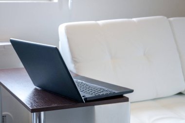 Gün ışığı alan, en az laptop ve beyaz kanepe. Zevk ile çalışmak