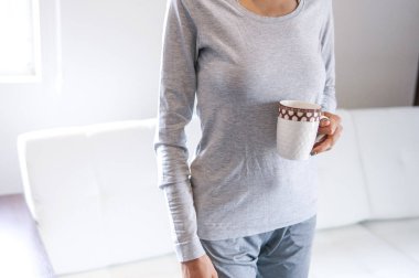 Bir fincan kahve, çay, kapuçino kadın elinde, gerçek görüntü bir beyaz odada rahat bir ev giyim