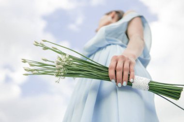 Gelini bir mavi elbise ile güzel çiçekler üzerinde mavi gökyüzü, görünümü Patellayı