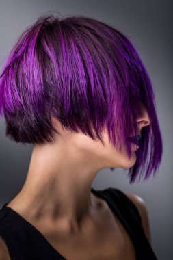 Gri arka plan üzerinde mor kısa saçlı kadın moda