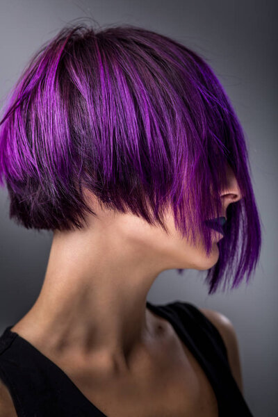 Fashion woman with purple short hair over gray background