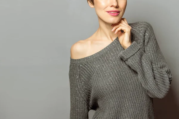 ファッション 灰色の背景に流行のセーターの若い女性 — ストック写真