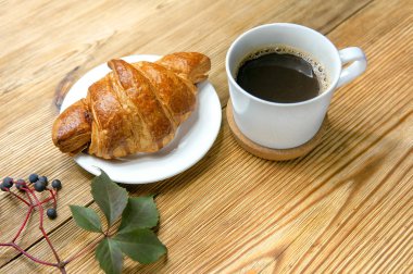 İyi ile sonbahar sabahı Fransız kruvasan, kahve ve sonbahar yaprakları ahşap rustik arka plan üzerinde