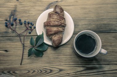 İyi ile sonbahar sabahı Fransız kruvasan, kahve ve sonbahar yaprakları ahşap rustik arka plan üzerinde