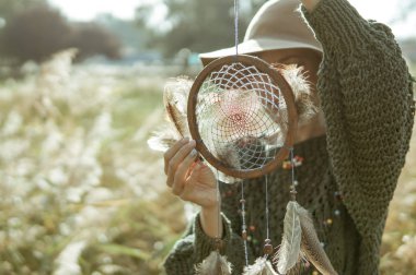 Güzel kadın bir rüya yakalayıcı bir güneşli sabah holding şapkası ve boho kıyafeti giymiş. Bir an kavram yaşamak