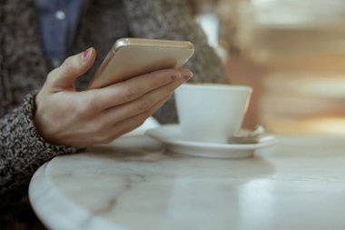 Bir kafede cep telefonu kullanan kadın