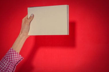 Kırmızı bir arka plan üzerinde tonlu görüntü boş kağıt tutan kadın el