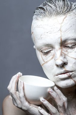 art portrait of woman covered in clay holding white  cup.  Kintsugi  concept clipart