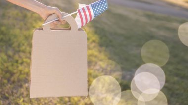 Anma Günü satış, Bağımsızlık Günü Satılık. Kadın el kağıt torba ve bahar ya da yaz Park Amerikan bayrağı