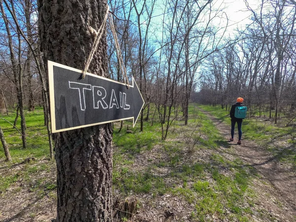 Traveling in early spring. Hiking sign pointing at a traveler walking along a forest trail