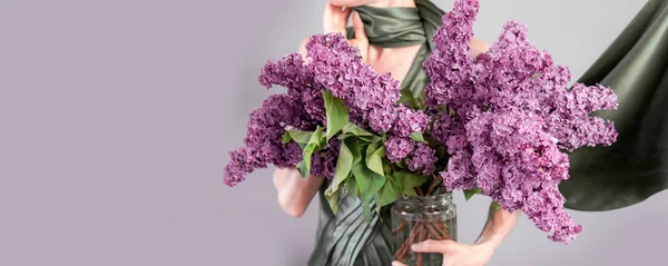 Elegant woman with a huge bouquet of purple lilac