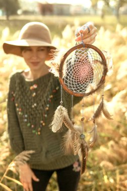 Güzel kadın bir rüya yakalayıcı bir güneşli sabah holding şapkası ve boho kıyafeti giymiş. Bir an kavram yaşamak