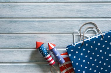 4 Temmuz tatil alışveriş konsepti. Ahşap arka plan üzerinde ulusal amerikan renkleri ve havai fişek roketler alışveriş çantaları