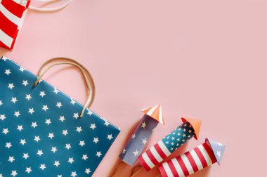 4 Temmuz tatil alışveriş konsepti. Pembe arka plan üzerinde ulusal amerikan renkleri ve havai fişek roketler alışveriş çantaları