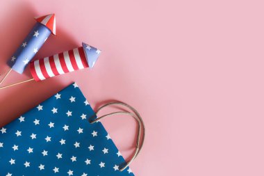 4 Temmuz tatil alışveriş konsepti. Pembe arka plan üzerinde ulusal amerikan renkleri ve havai fişek roketler alışveriş çantaları