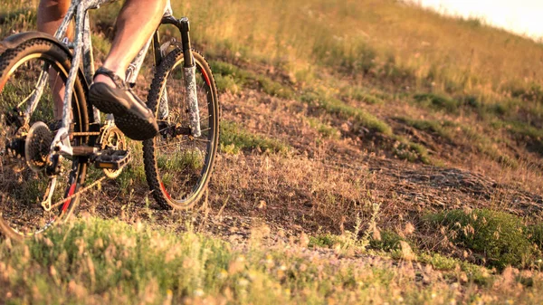 日落时骑自行车的人骑自行车沿着岩石山走 关闭极限运动理念 — 图库照片