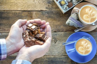 Adam ahşap romantik tarih arka plan üzerinde elinde fındık ile çikolata tam ellerini tutarak