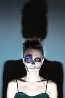 Halloween. Parlak siyah cadılar bayramı makyaj ve koyu gri arka plan üzerinde izole arkasında büyük gölge ile güzel kadın