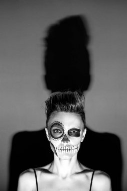 Halloween. Parlak siyah cadılar bayramı makyaj ve koyu gri arka plan üzerinde izole arkasında büyük gölge ile güzel kadın