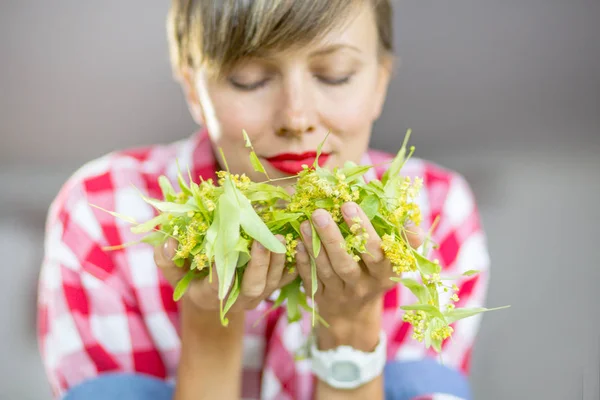 女人拿着林登花 享受它的香气 — 图库照片