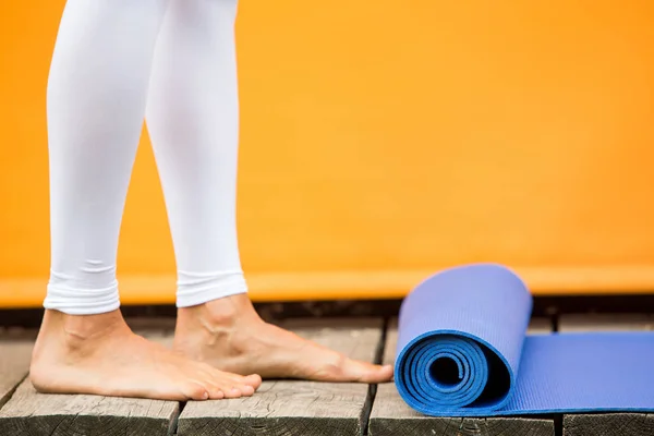 Sporty yoga girl with yoga mat wearing sport clothes over orange background