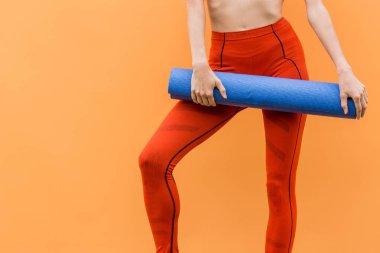 Turuncu arka plan üzerinde spor giysiler giyen yoga mat ile Sportif yoga kız