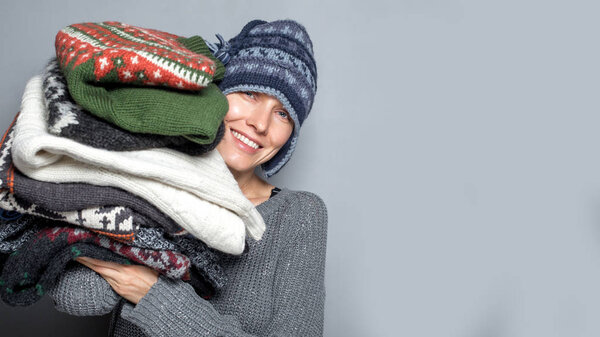 Осень или зимняя женщина. Портрет молодой женщины с кучей свитеров в вязаной шляпе и тёплом шерстяном свитере
