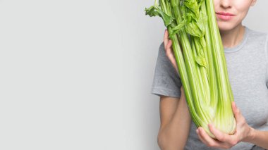 Elinde yeşil taze kereviz tutan bir kadın. Sağlıklı beslenme, vejetaryen yemekleri, diyet ve insanlar konsepti