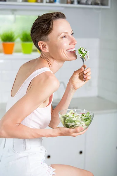 Молодая Женщина Ест Здоровую Пищу Сидя Красивом Интерьере Белой Кухни — стоковое фото