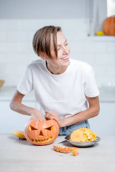 Beautiful young woman  with pumpkin in white kitchen