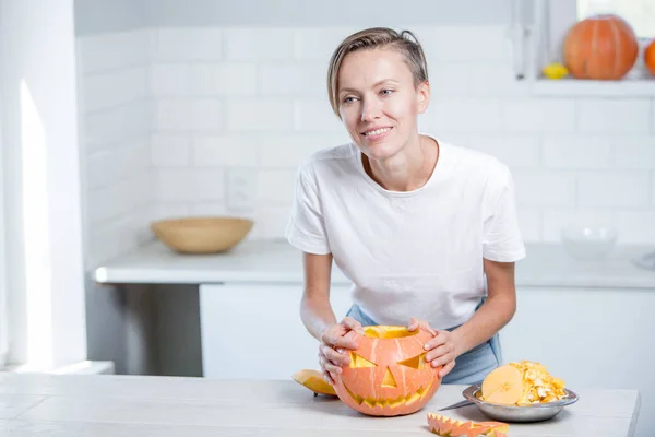 Beautiful young woman  with pumpkin in white kitchen