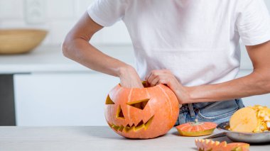 Beyaz mutfağında balkabağı olan güzel, komik genç bir kadın.