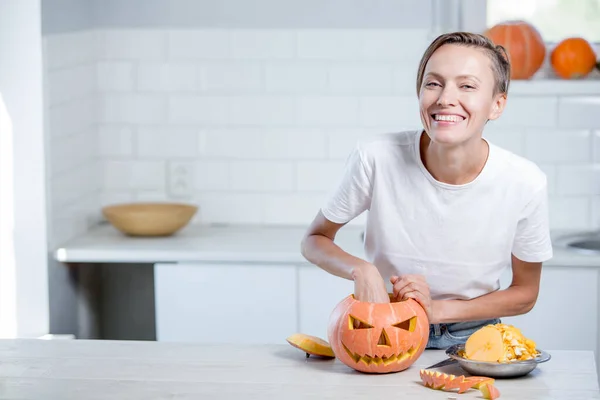 Beautiful funny young woman  with pumpkin in white kitchen