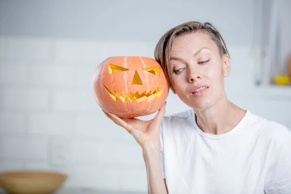 Beautiful funny young woman  with pumpkin in white kitchen