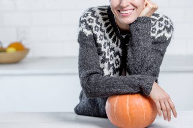 Beyaz mutfakta turuncu balkabağı olan kazaklı güzel bir kadın.