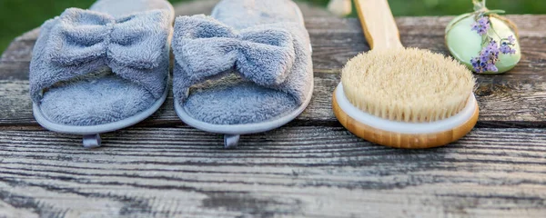 Spa day concept. Spa and wellness setting with bathrobe, brush, soap with lavender scent, slippers