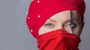 Gri arka planda izole edilmiş virüsü önlemek için eşarp maskesi takan çekici ve şık bir kızın portresi.