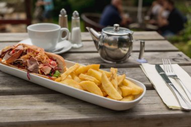 Gündelik yemek, piknik havası, öğle yemeği fikri. Yemek blogları ve açık hava yemekleri için mükemmel. Sandviç ve kızarmış patatesle dışarıda hızlı bir öğle yemeği.